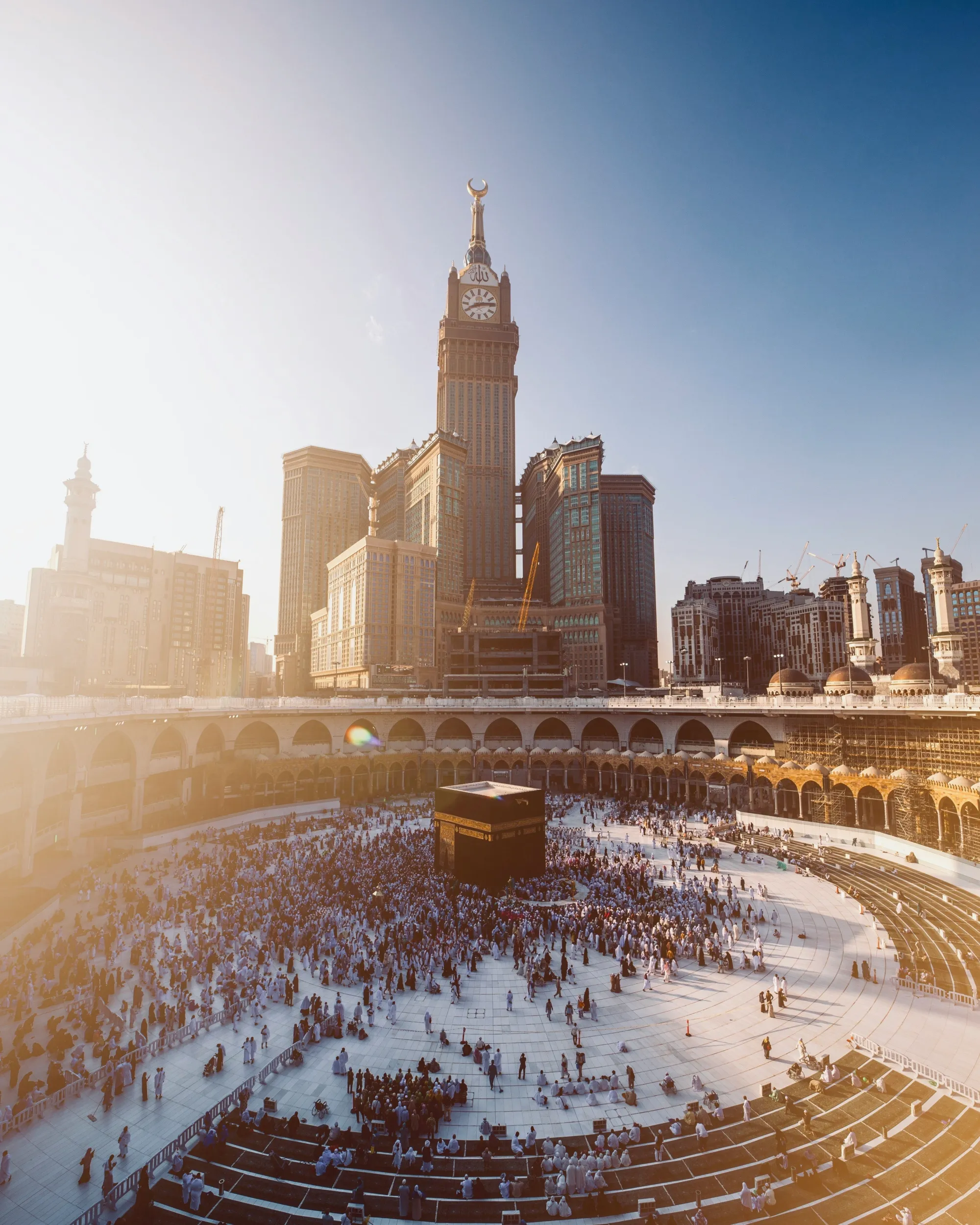 The plaza and minarets of Masjid al-Haram under a clear sky, representing Makkah's seasonal weather